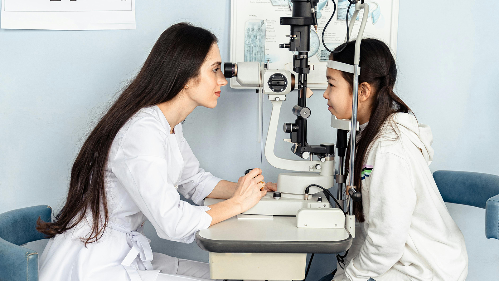 A woman looks through a phoropter during a vision test, a crucial part of determining an eyeglass prescription.