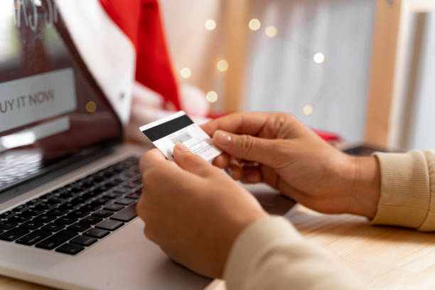 A person holding a credit card in front of a laptop, ready to make an online purchase.