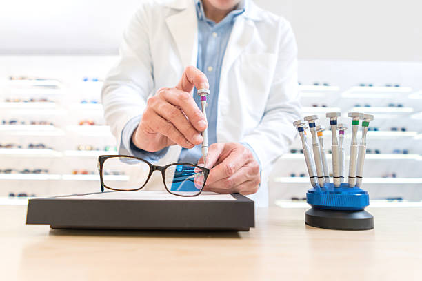 An optometrist is adjusting a pair of eyeglasses using a small tool