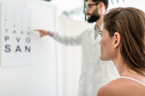 An optometrist is helping a female patient with a vision test