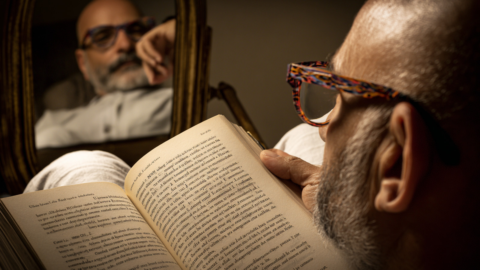 A cozy lifestyle shot of a man wearing stylish reading glasses while reading a book, reflected in a mirror to illustrate comfortable vision correction.