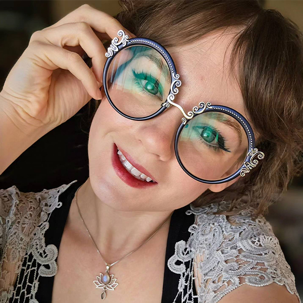 A smiling woman wearing large, round eyeglasses with decorative frames.