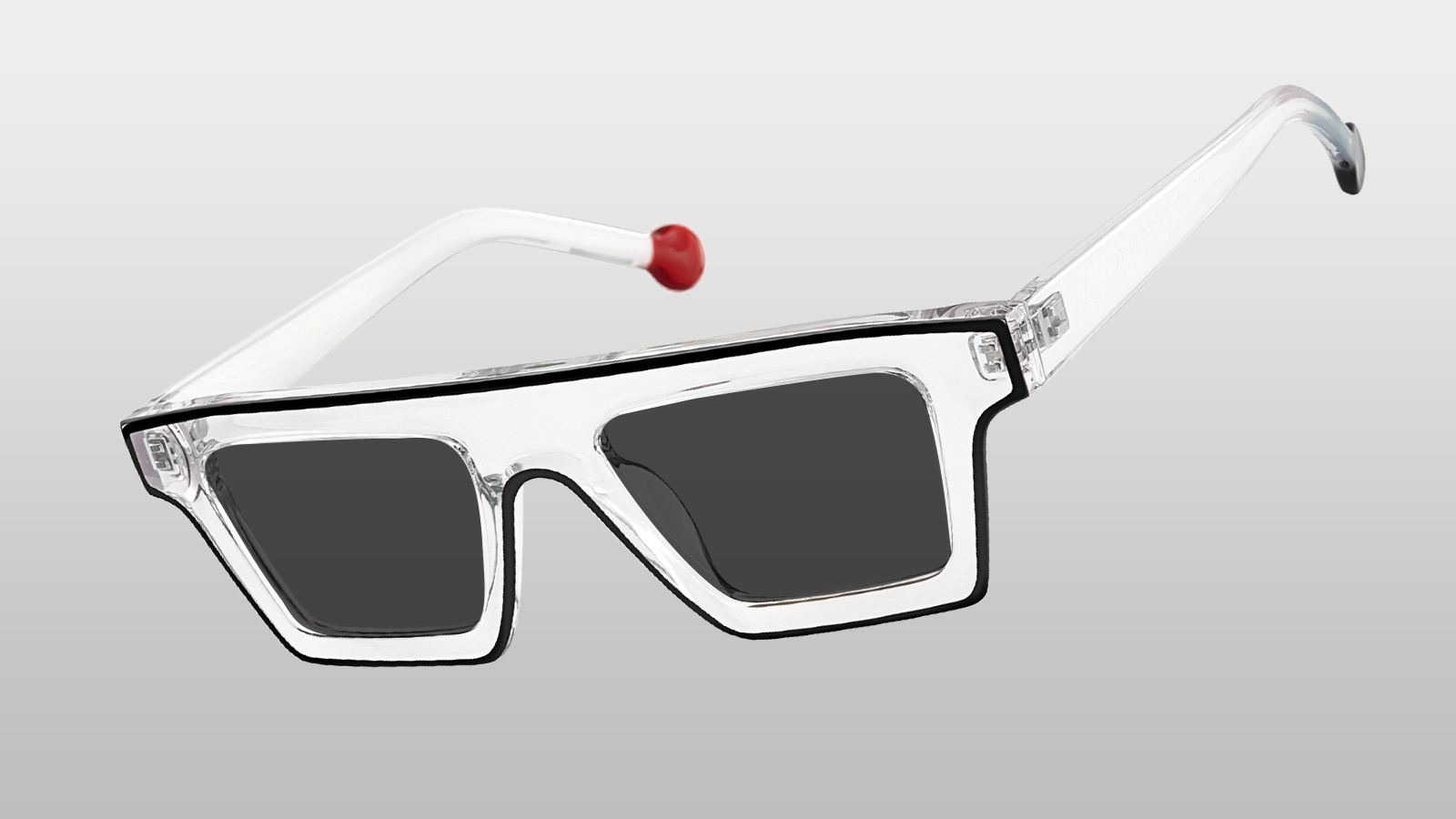A pair of power-minimalist rectangular sunglasses with clear frames and a unique red-tipped arm, highlighting 2026 clean-line trends.