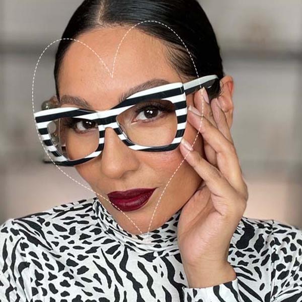 A woman wearing bold, black and white striped glasses with a heart-shaped face